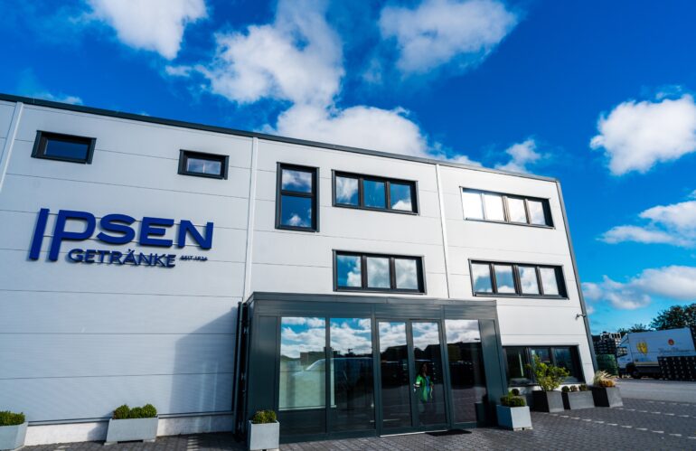 Ein zweistöckiges Gebäude mit einem Schild mit der Aufschrift „Ipsen“ auf der Vorderansicht.