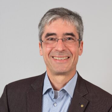 Ein Mann mit Brille aus einem Unternehmen lächelt in die Kamera.