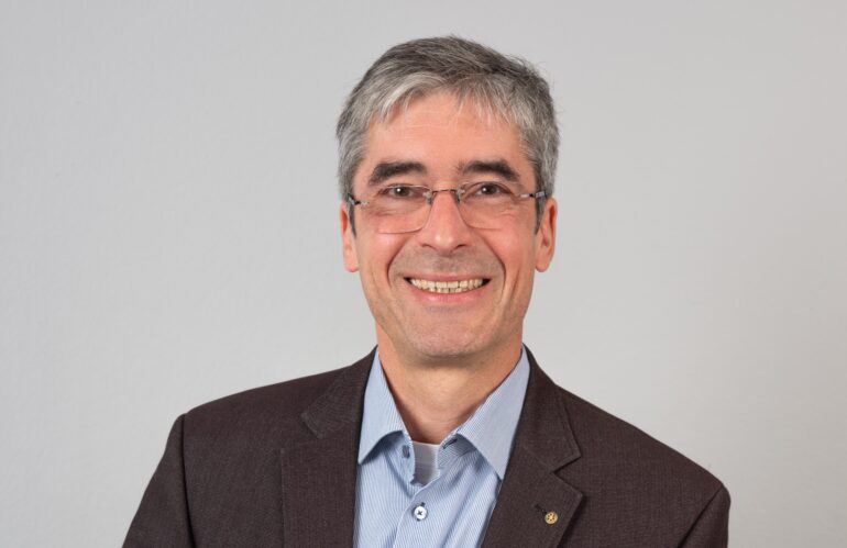 Ein Mann mit Brille aus einem Unternehmen lächelt in die Kamera.